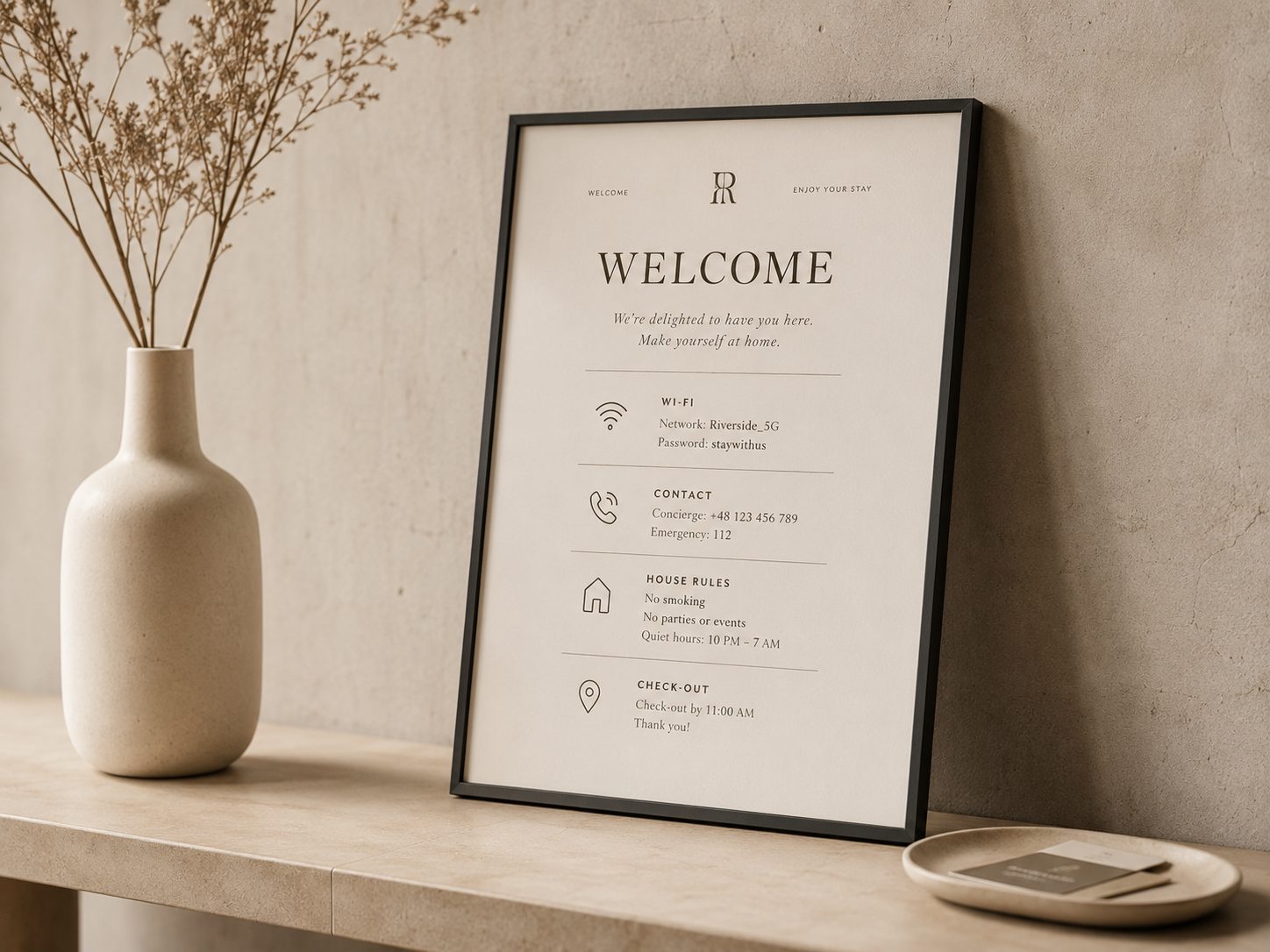 A framed welcome card on a stone console, listing the Wi-Fi network and password, contact numbers, house rules and the check-out time